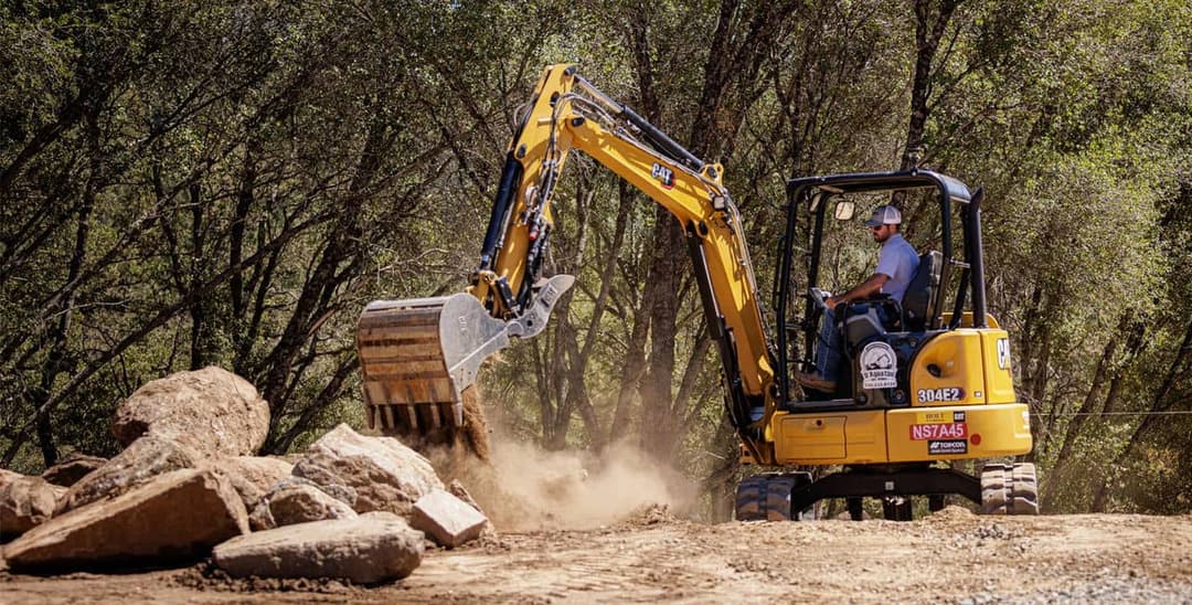 Miniexcavadora excavando zanja en obra urbana