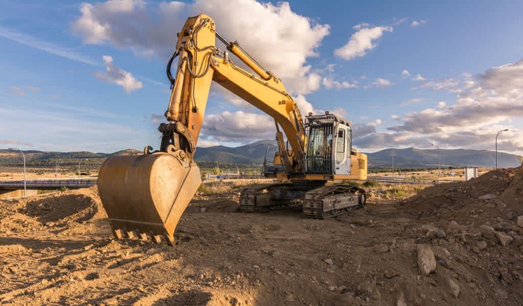 Operador certificado manejando una retroexcavadora con brazo largo